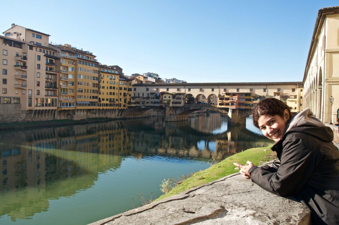 Portrait of young woman in warm clothing standing by canal in city