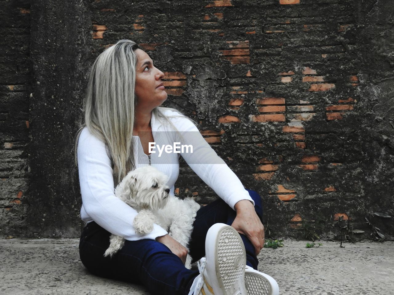 Woman with dog sitting against wall