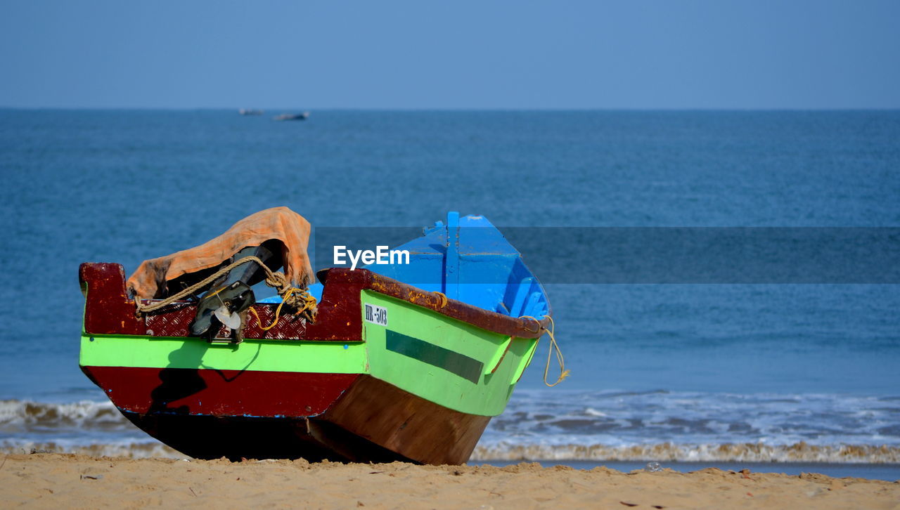 Boat moored at beach against clear sky