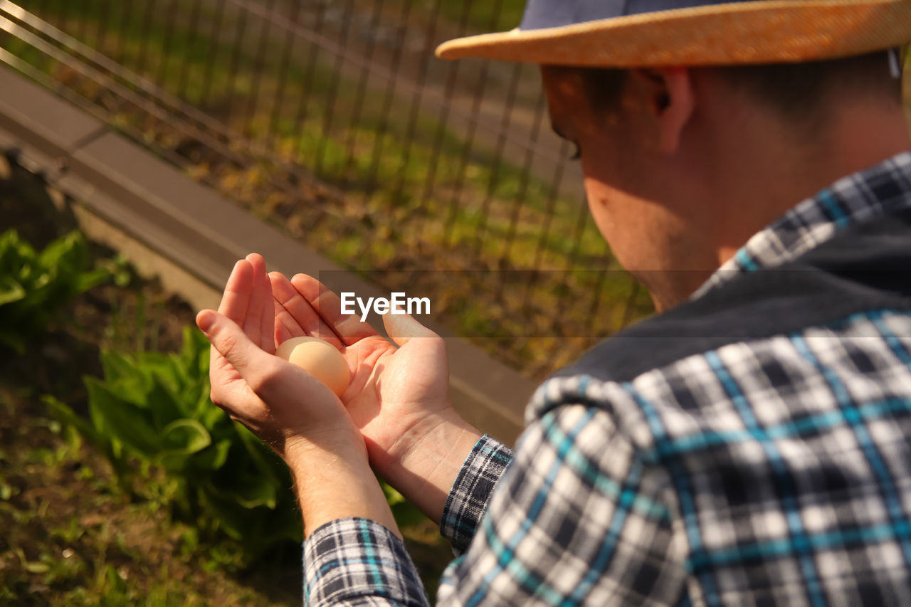 Human hands hold a chicken egg. top view male hands holding one brown egg. easter. business 