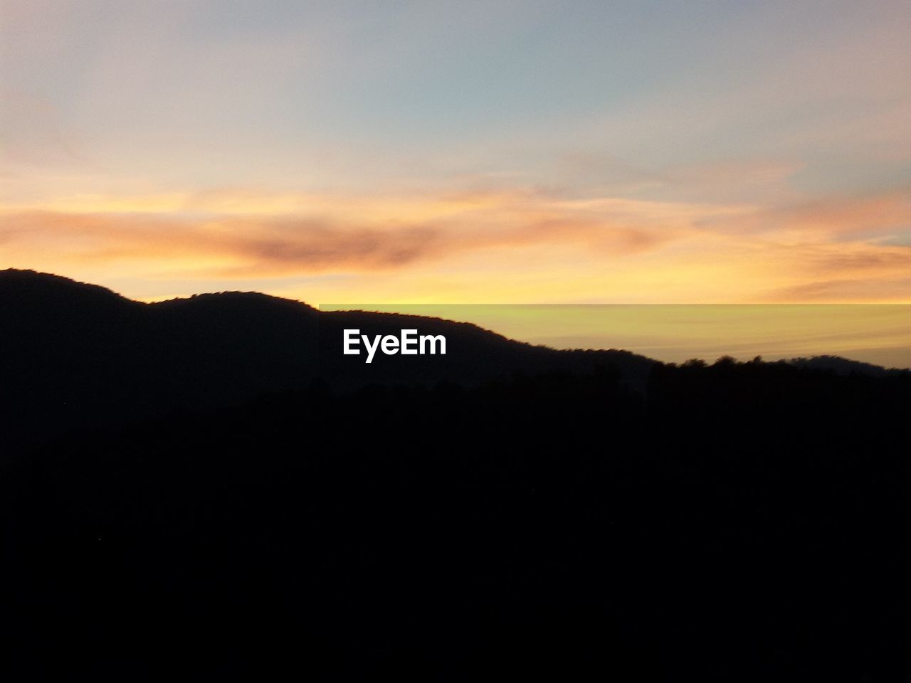 SCENIC VIEW OF SILHOUETTE MOUNTAIN AGAINST ORANGE SKY