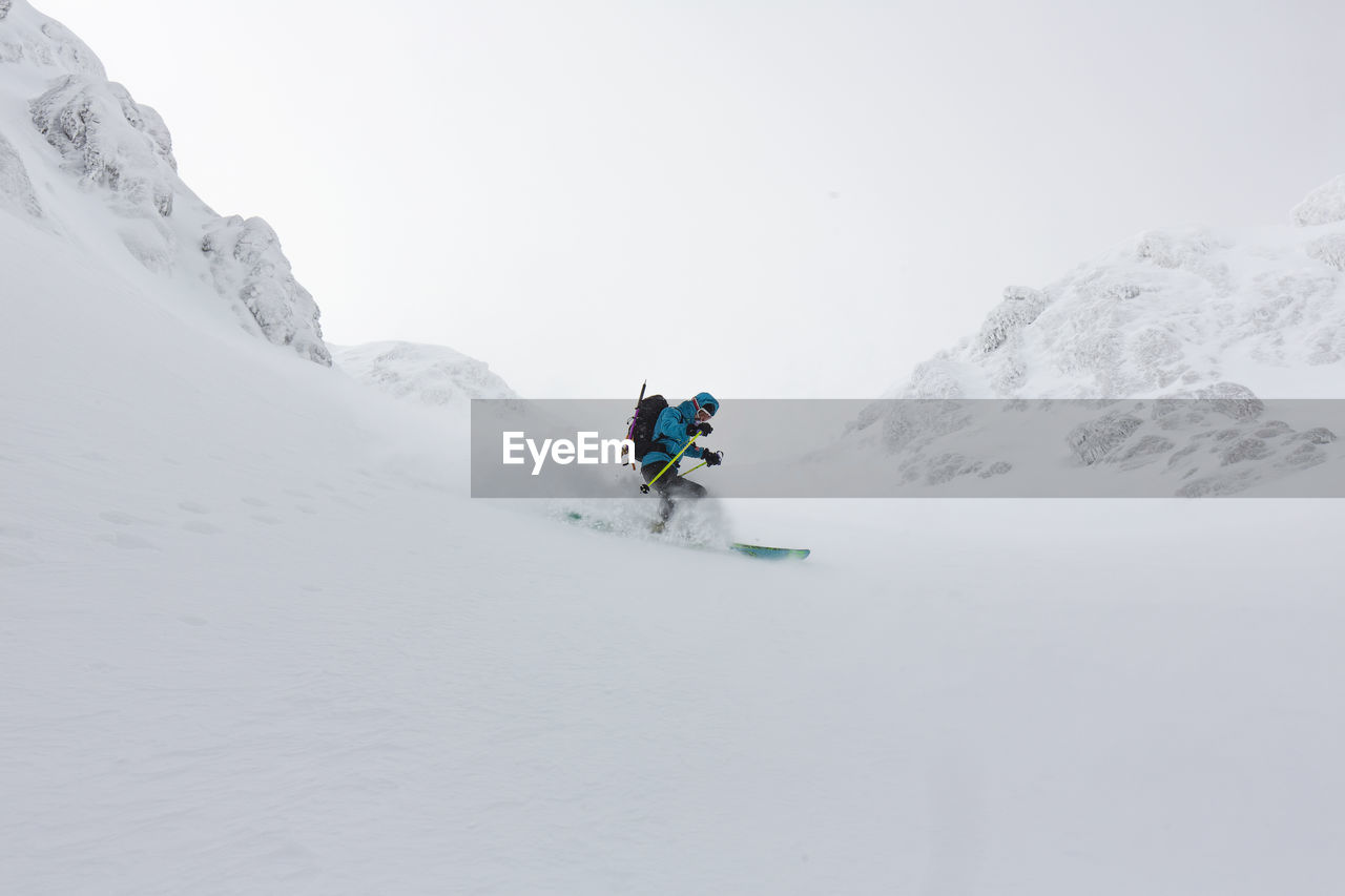 Young man skiing on snowcapped mountain against sky