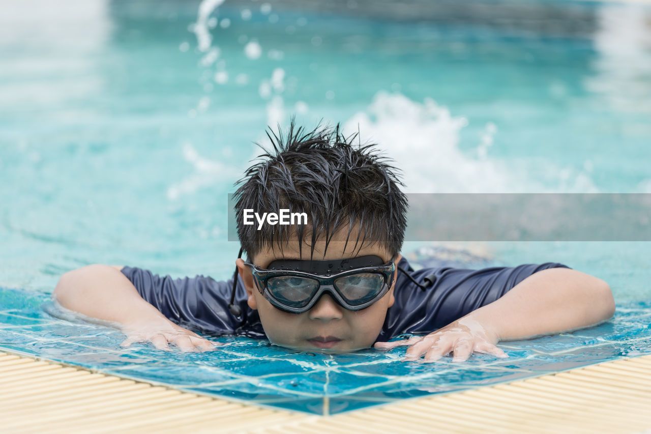 Boy happy swimming in a pool. children swimming and playing in water.