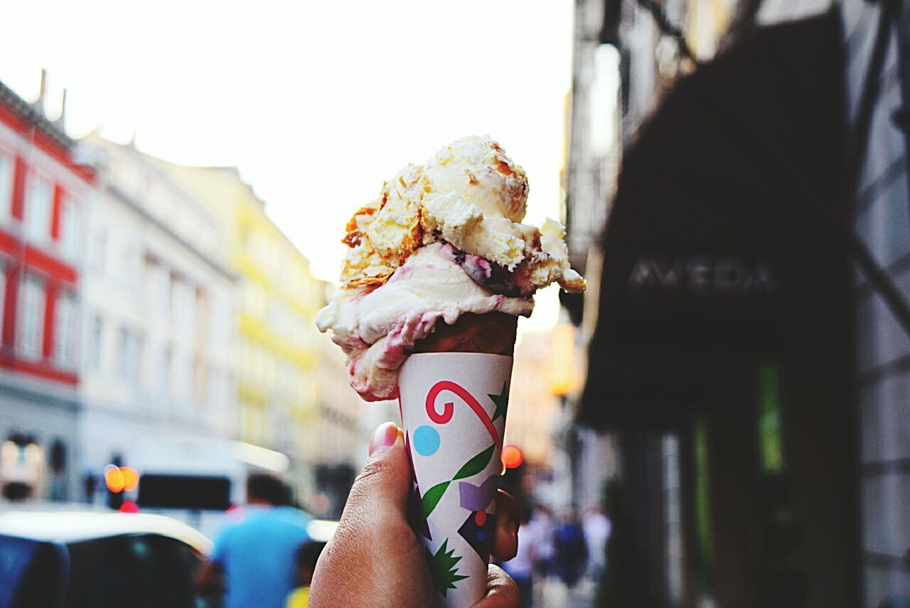 Cropped image of hand holding ice cream cone in city