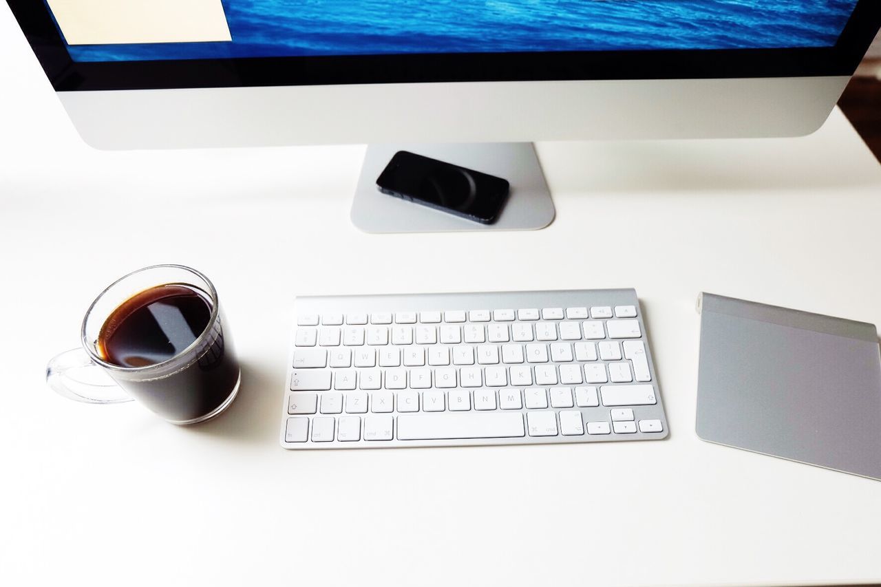 High angle view of black coffee by keyboard on desk