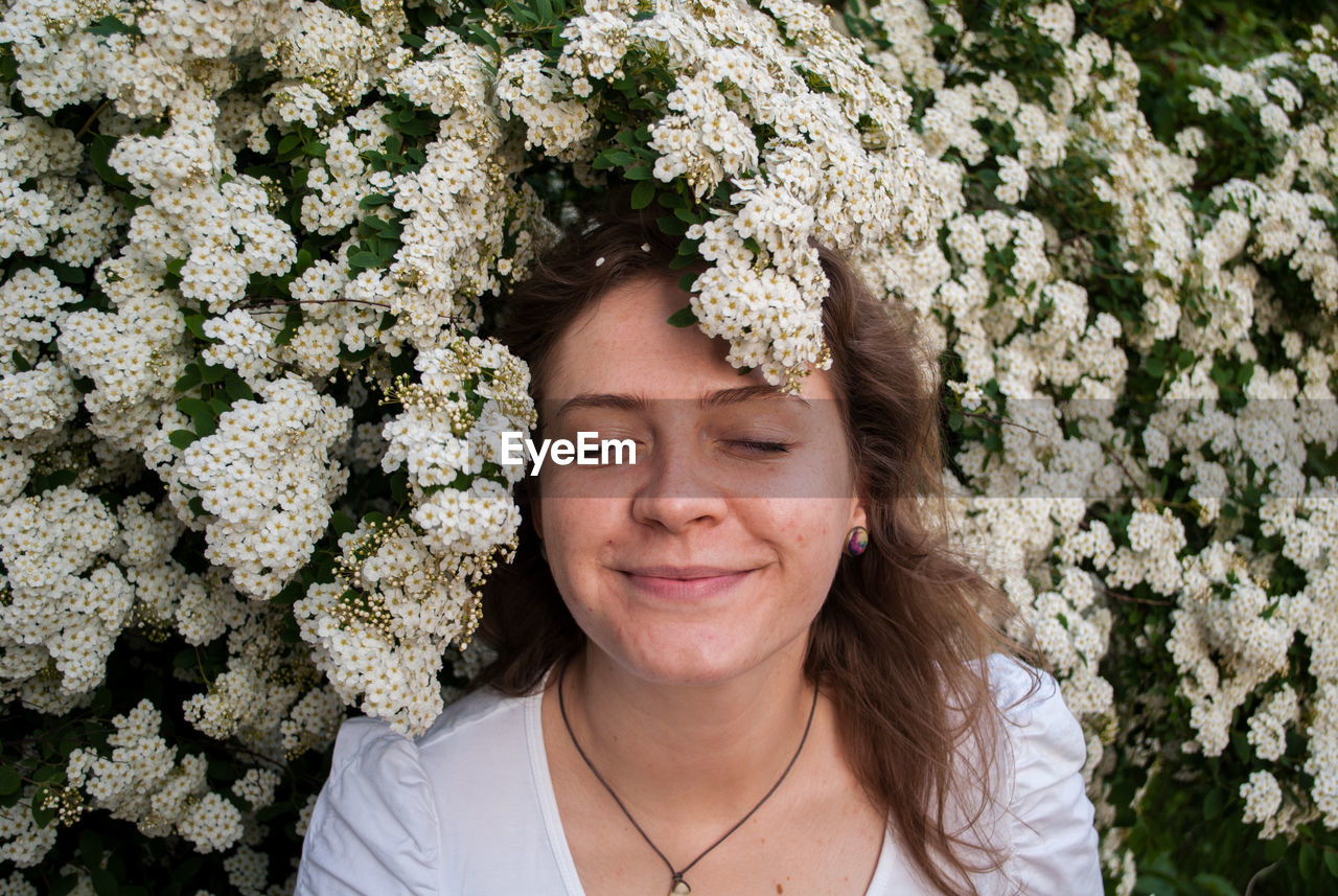 Portrait of young woman standing against tree blossum