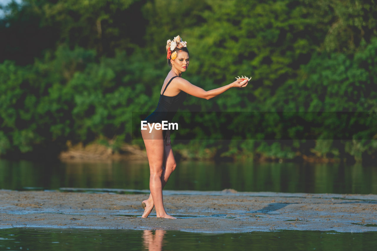 Full length of woman standing by lake