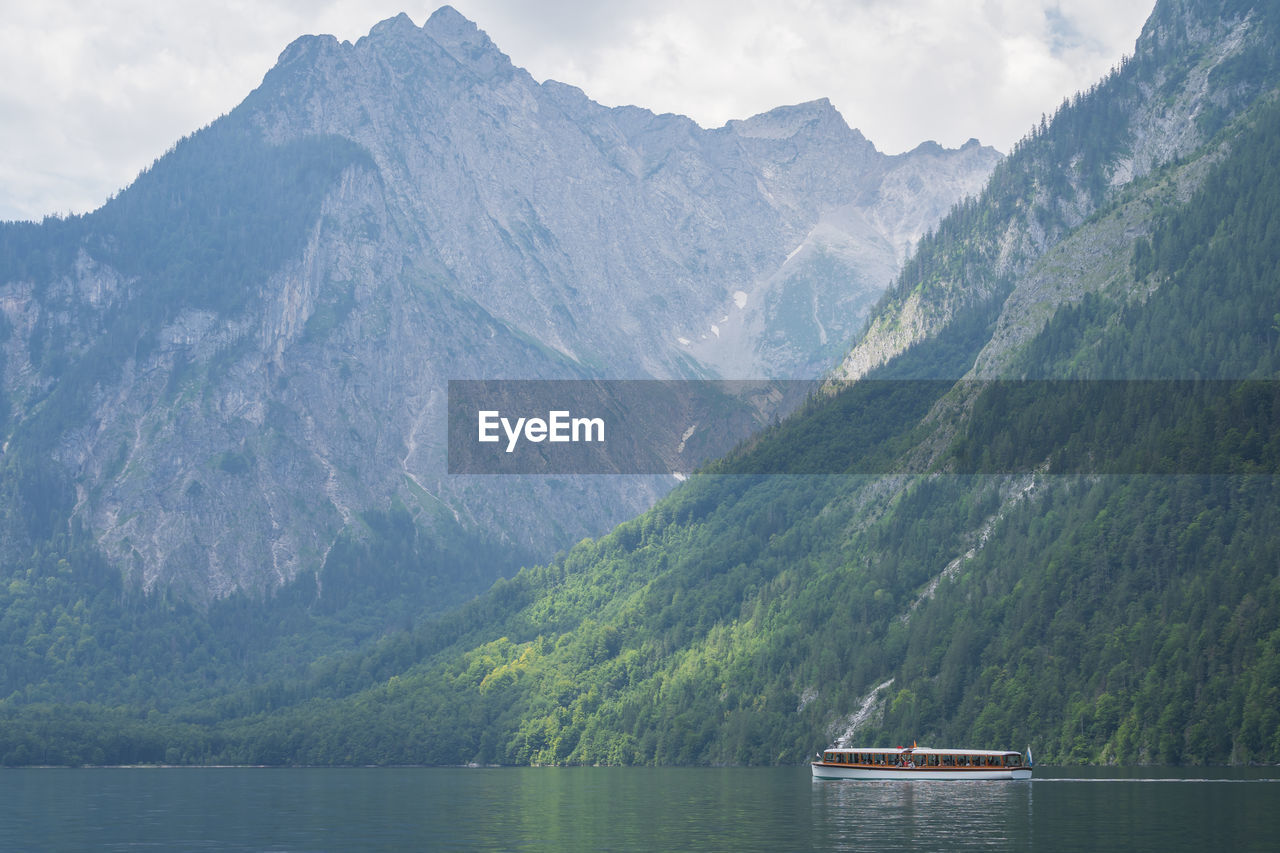 Small boat sailing on alpine lake surrounded by high mountains , konigssee, germany