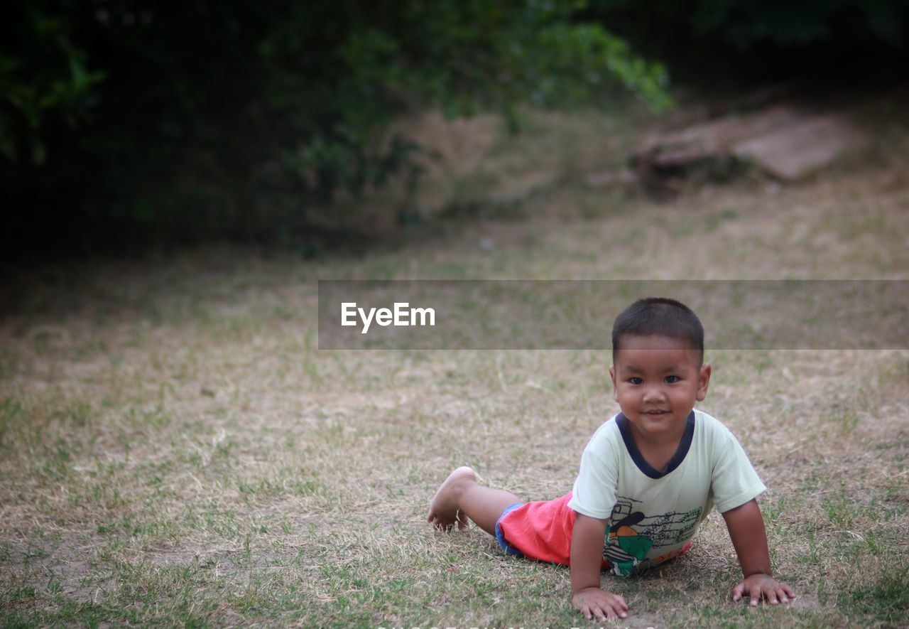 Portrait of smiling boy lying on grassy field