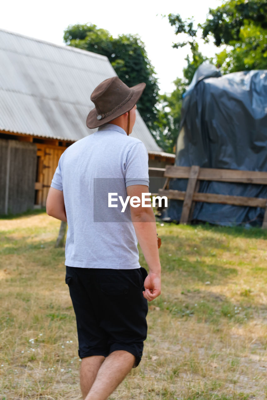 Male in hat. portrait of smiling farmer with green grass and trees nature in background. young man