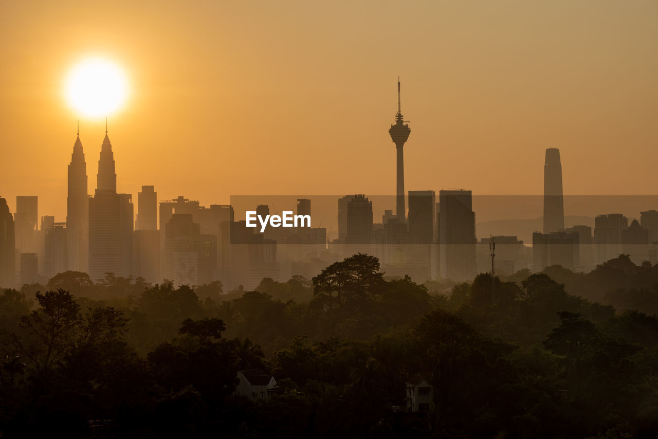 Modern buildings in city against sky during sunset
