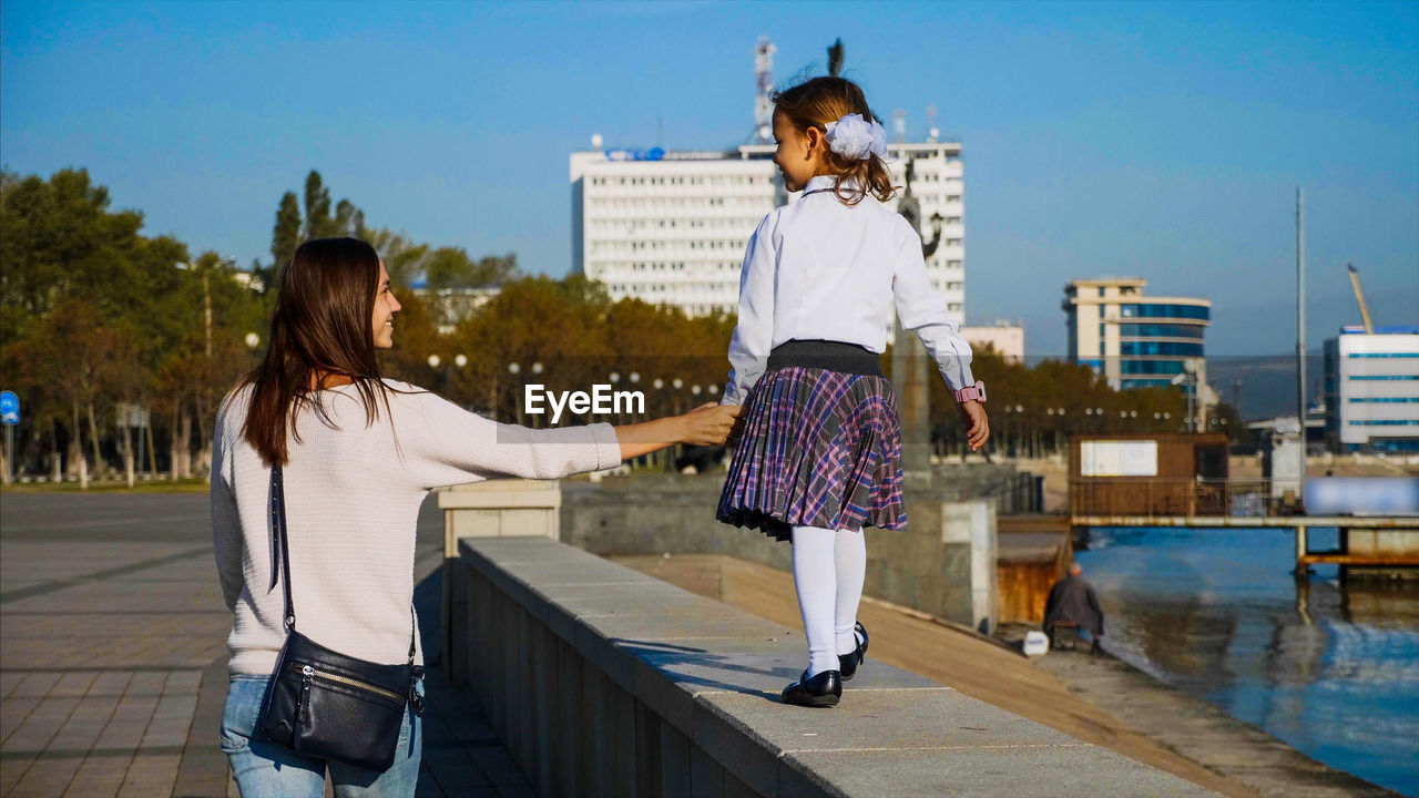 Rear view of mother with daughter walking in city