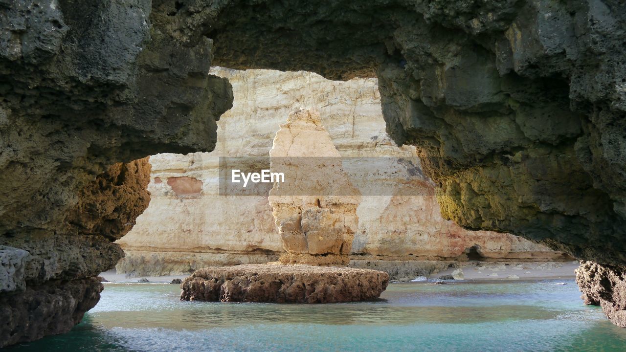 Rock formation in sea behind cave