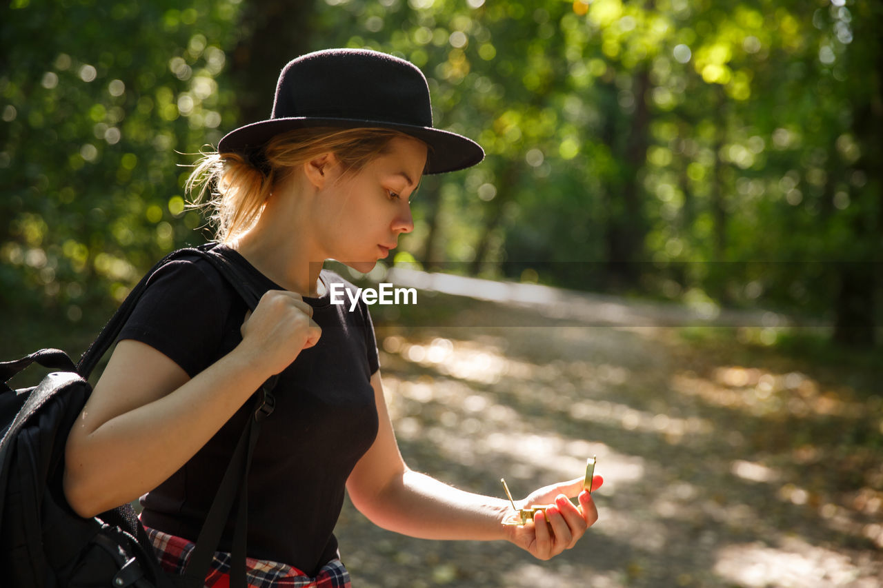 portrait of young woman wearing hat standing in forest