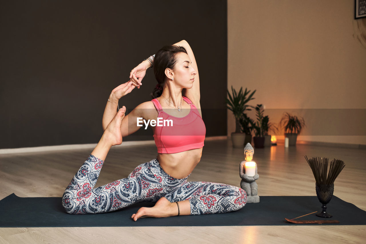 Young woman doing yoga on yoga mat in atmospheric yoga studio