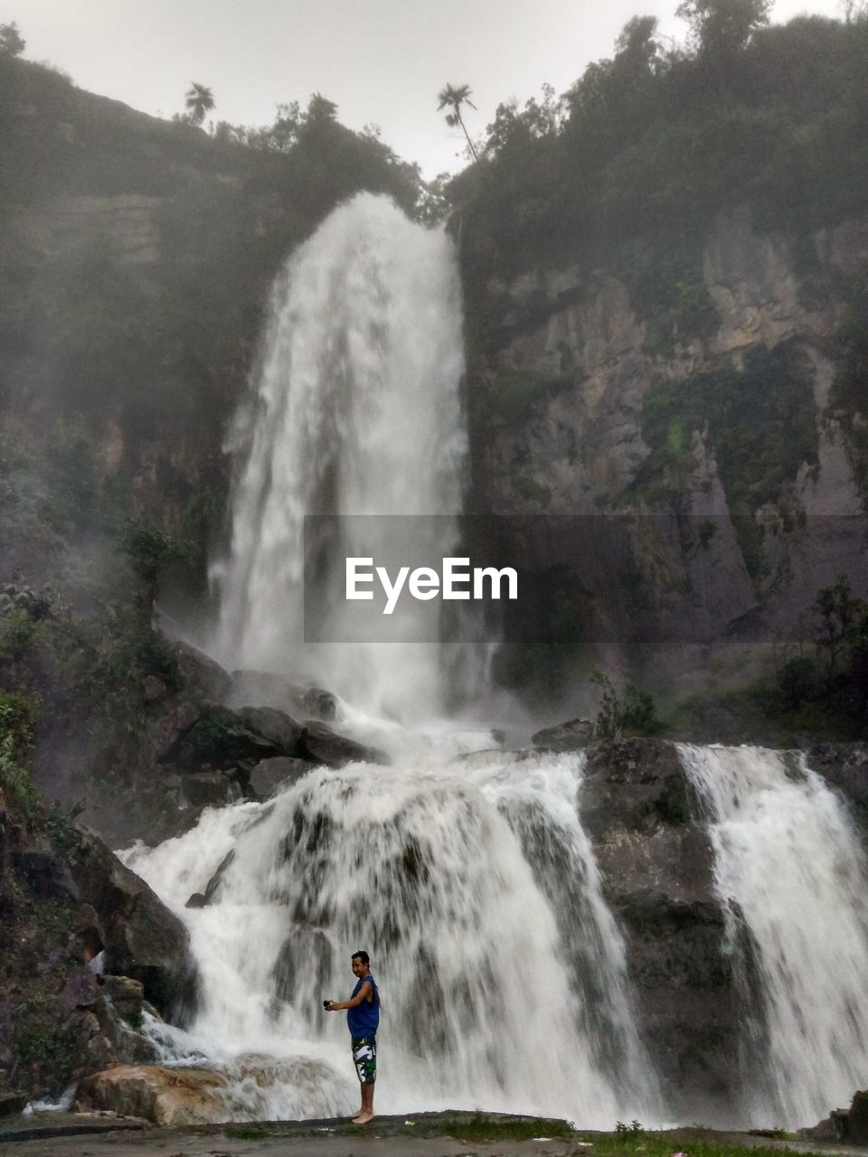 Man standing against waterfall