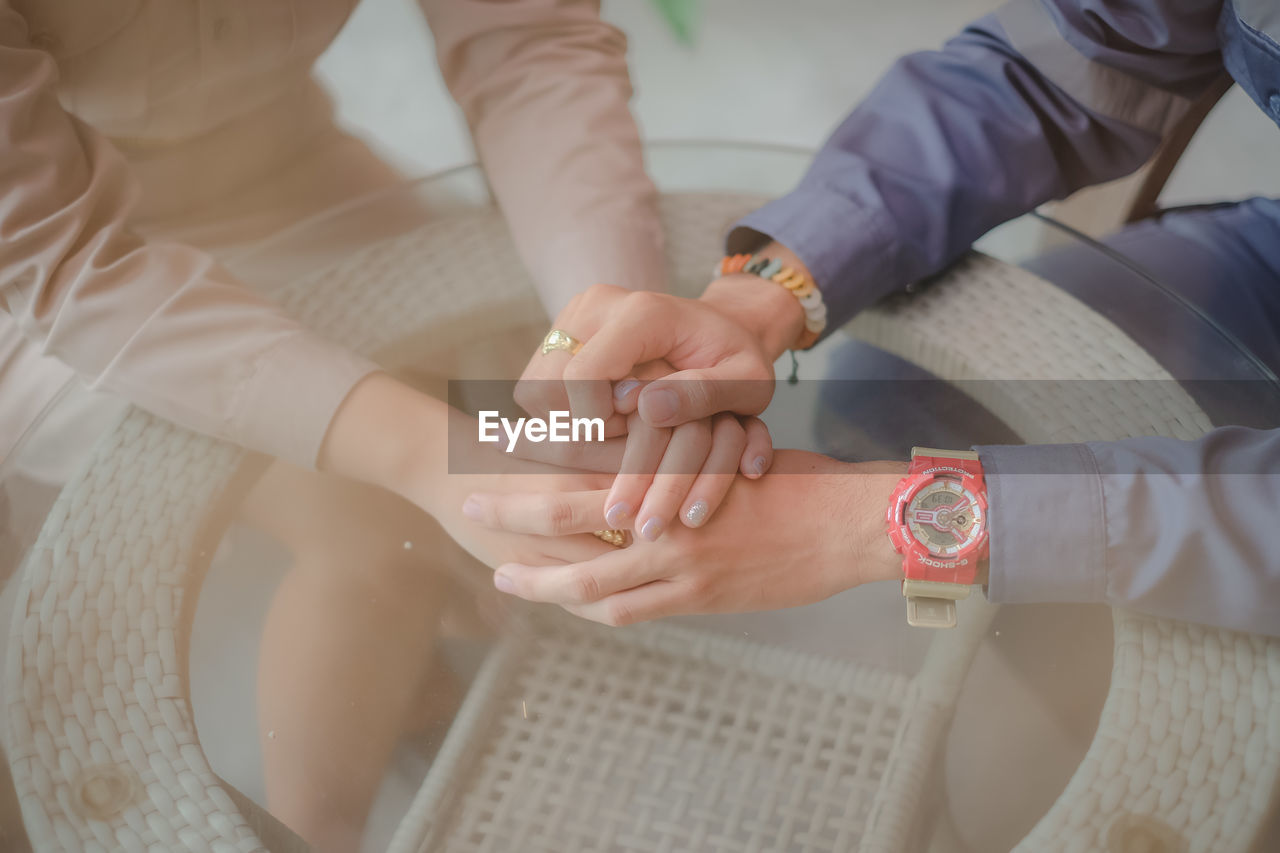 Midsection of couple holding hands at table