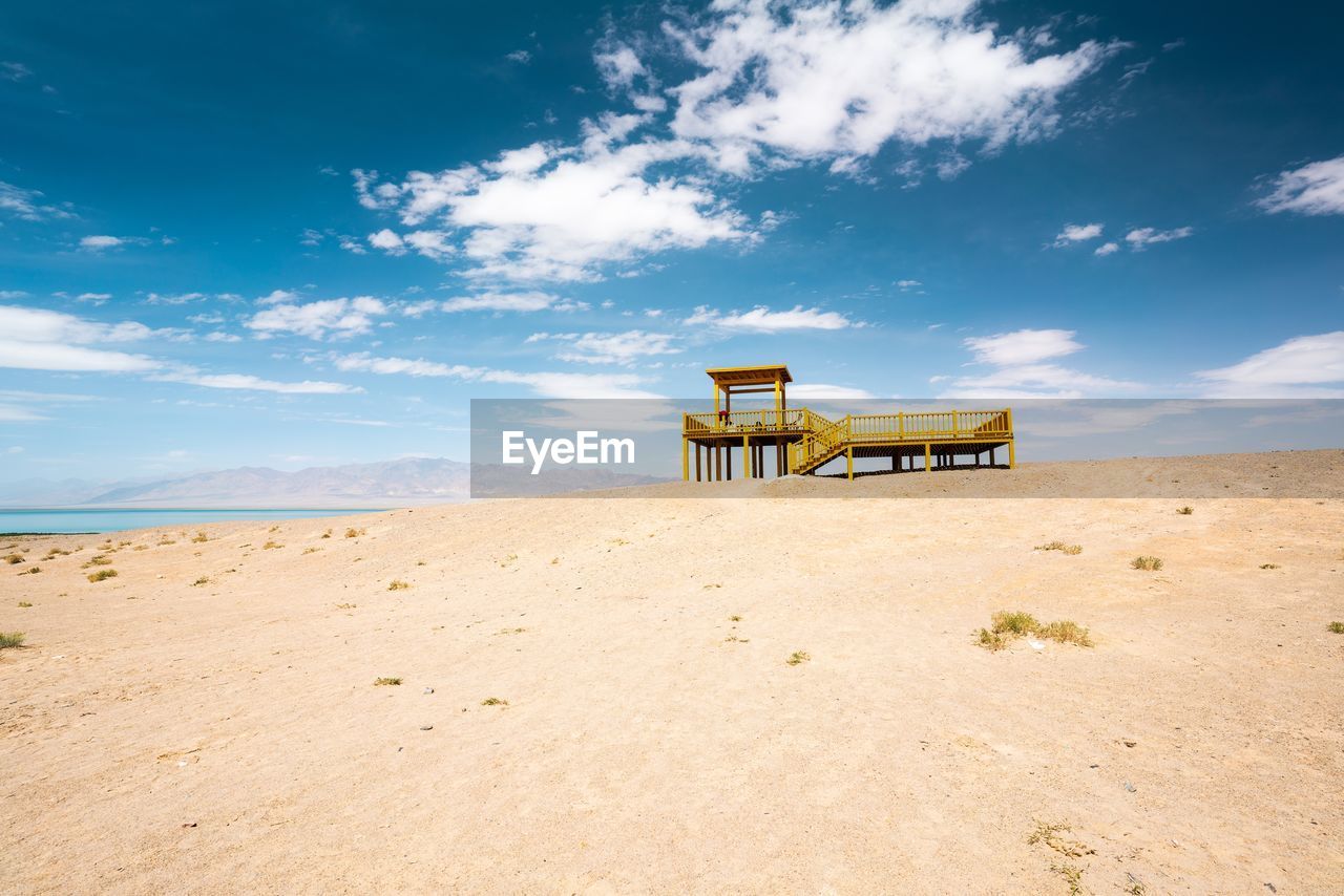 LIFEGUARD HUT ON SAND AGAINST SKY
