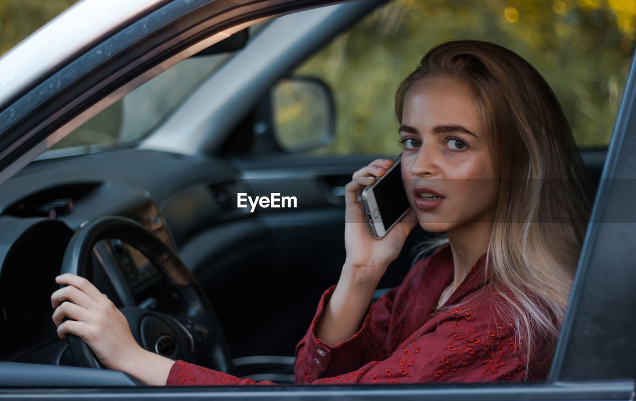 YOUNG WOMAN USING MOBILE PHONE IN CAR