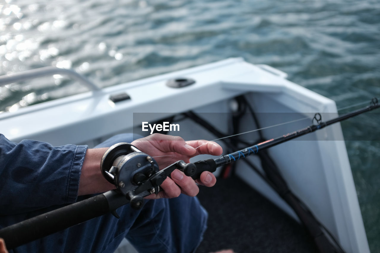 Close-up of human hand holding fishing rod in river