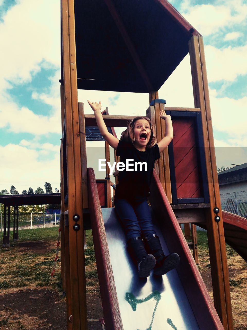 Full length of girl screaming on slide at playground