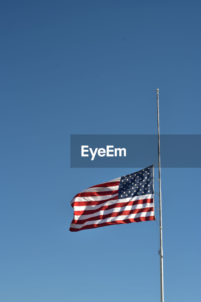 Low angle view of american flag against clear blue sky