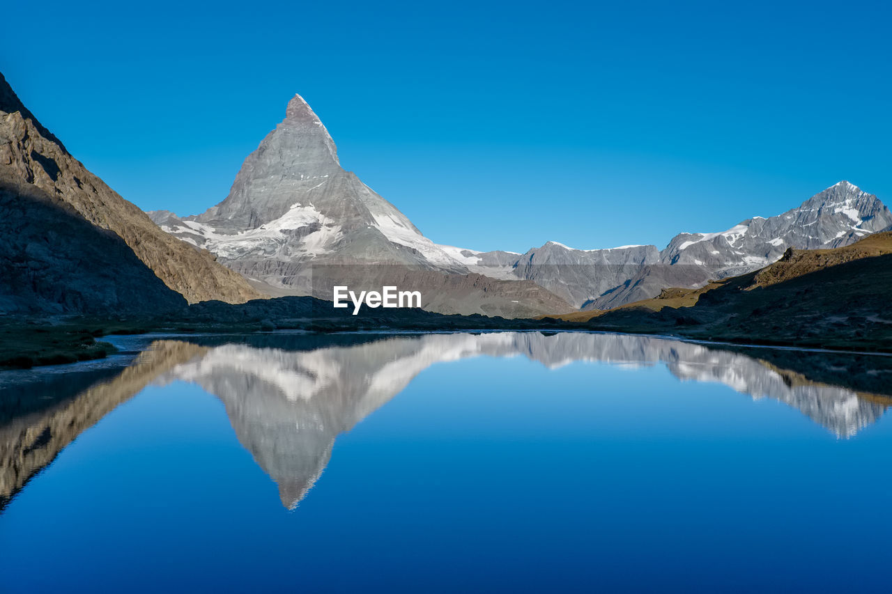 Scenic view of  matterhorn reflected in mountain lake against clear blue sky