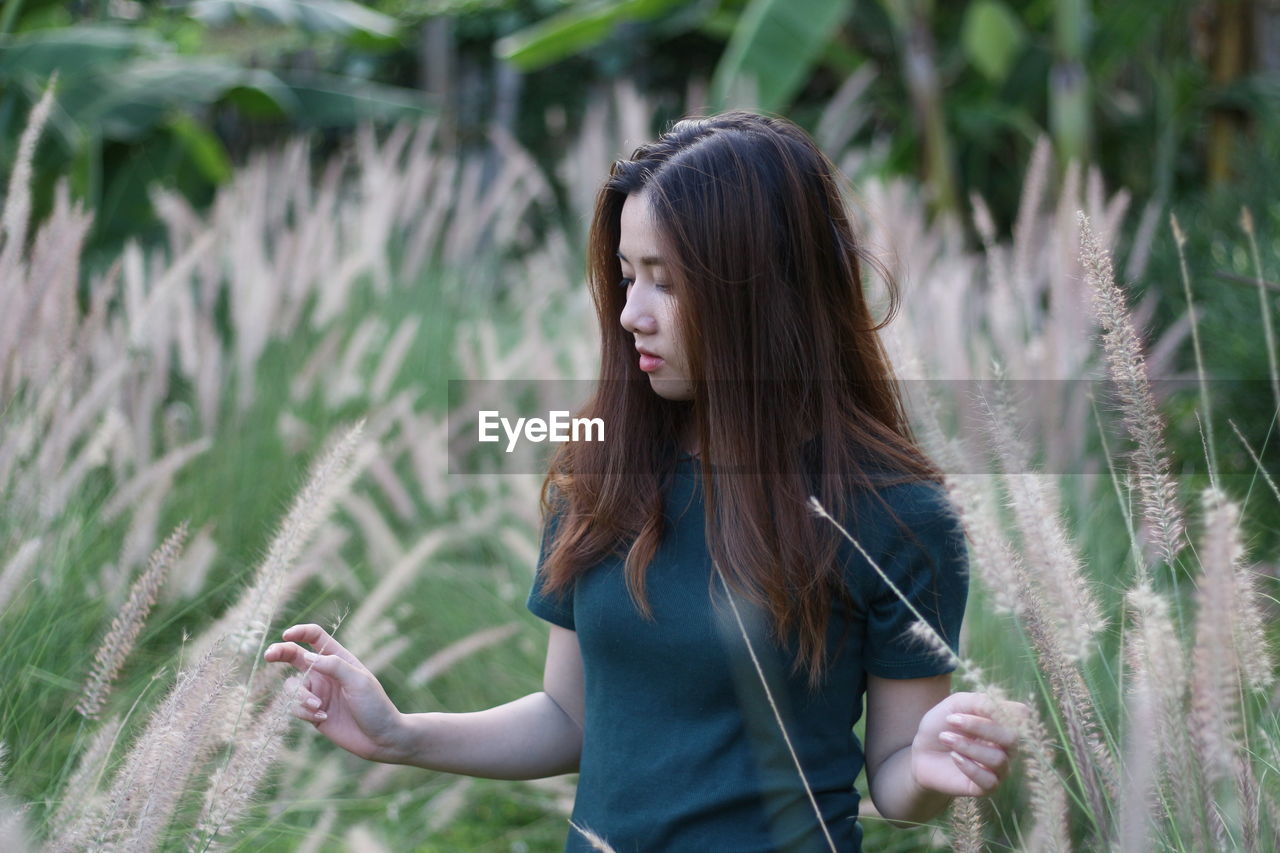 Young woman standing amidst plants on field