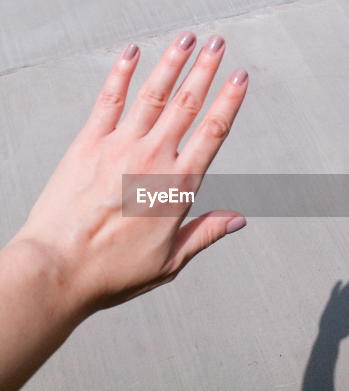 CLOSE-UP OF WOMAN HAND WITH TATTOO ON FLOOR