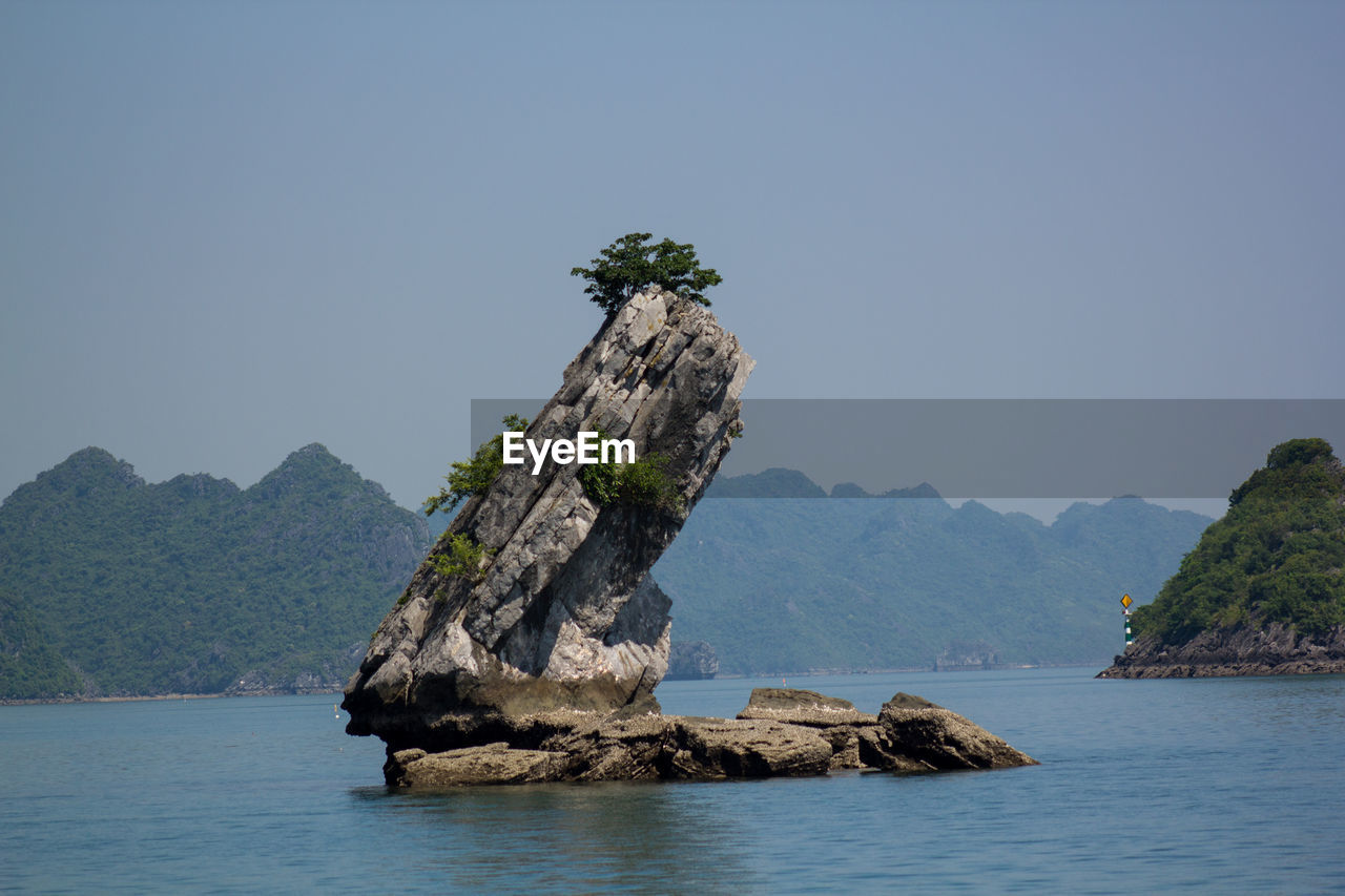 Rock formation in sea against clear sky