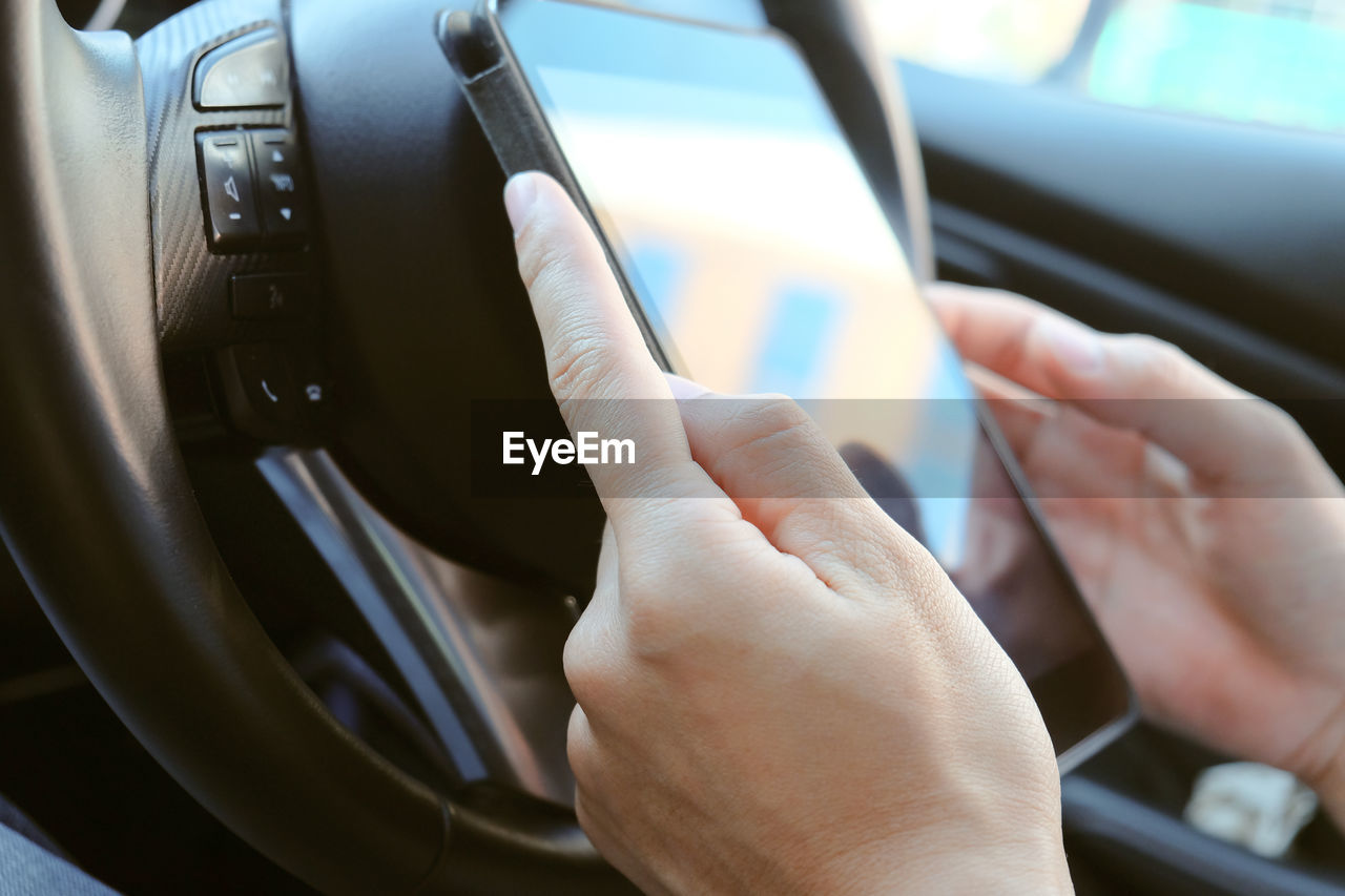 Cropped hand of person using mobile phone in car