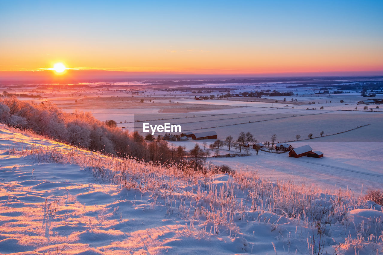 Scenic view of snow covered land during sunset