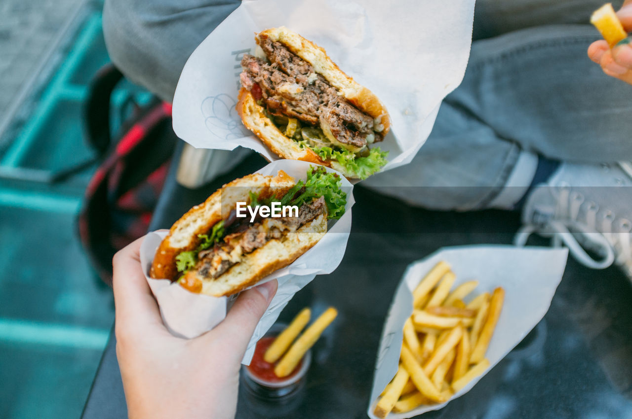 Cropped image of friends holding burger