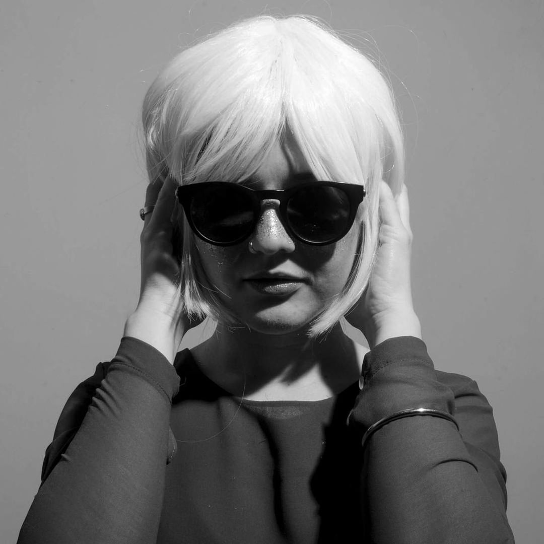 Close-up portrait of young woman wearing sunglasses against gray background