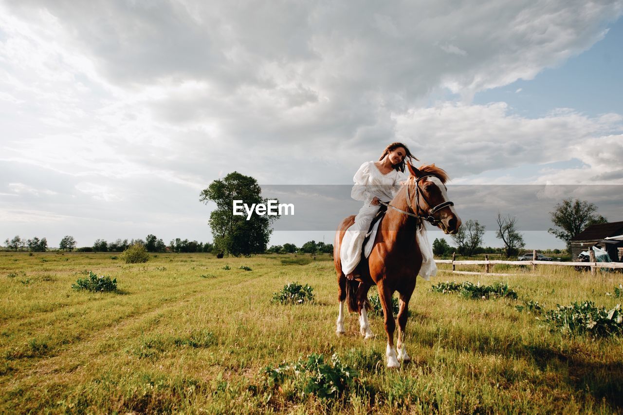 Young woman riding horse on field