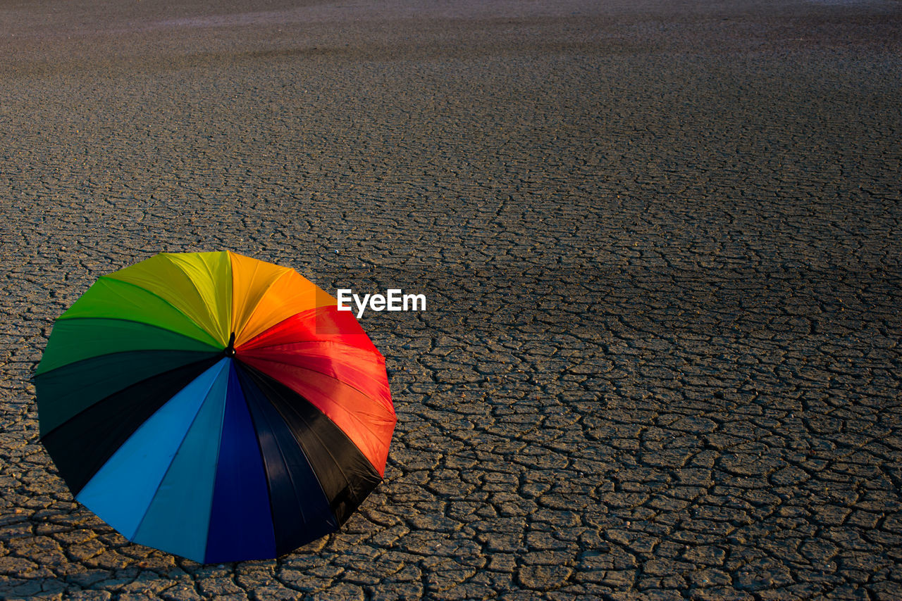 High angle view of multi colored umbrella on drought land