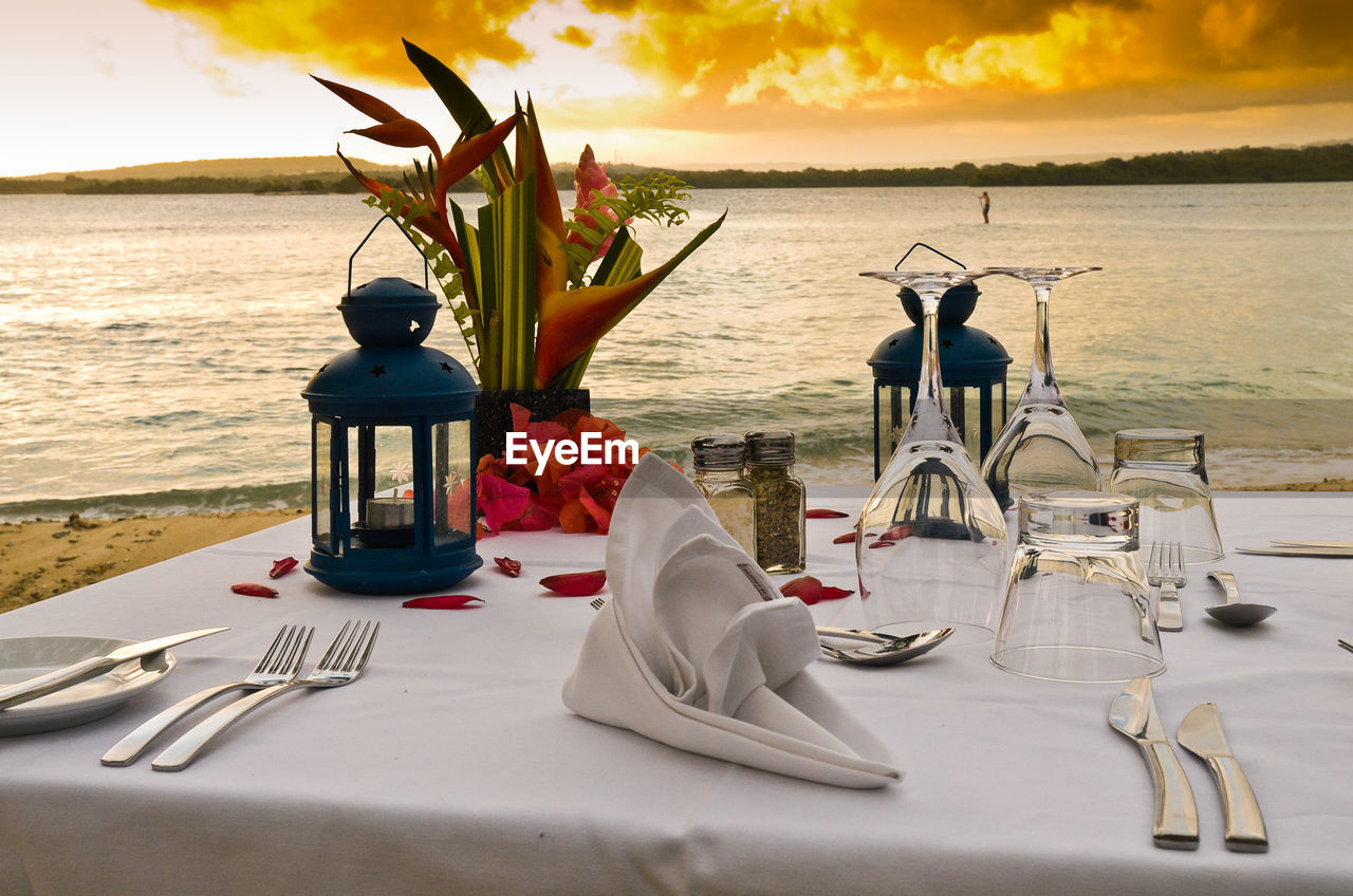 Place setting on table at beach during sunset