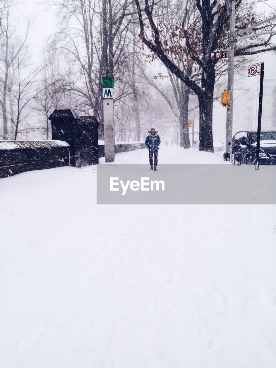 WOMAN WALKING ON SNOW COVERED LANDSCAPE