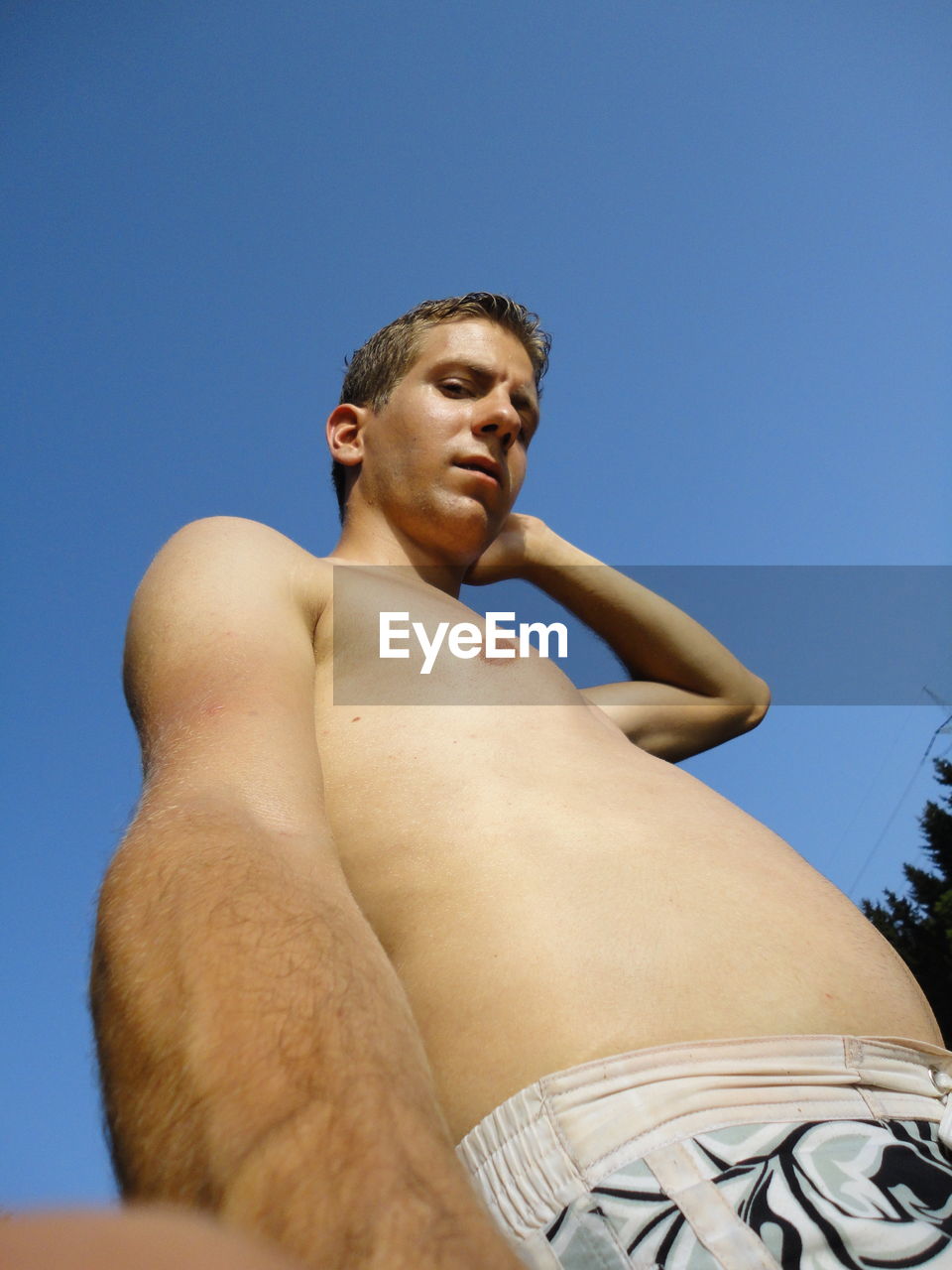 Portrait of shirtless man against clear blue sky