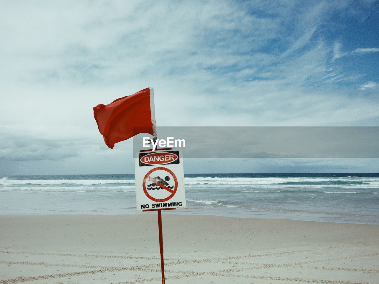 No swimming sign at beach against sky