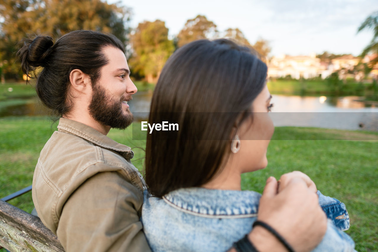 side view of young woman looking away against trees