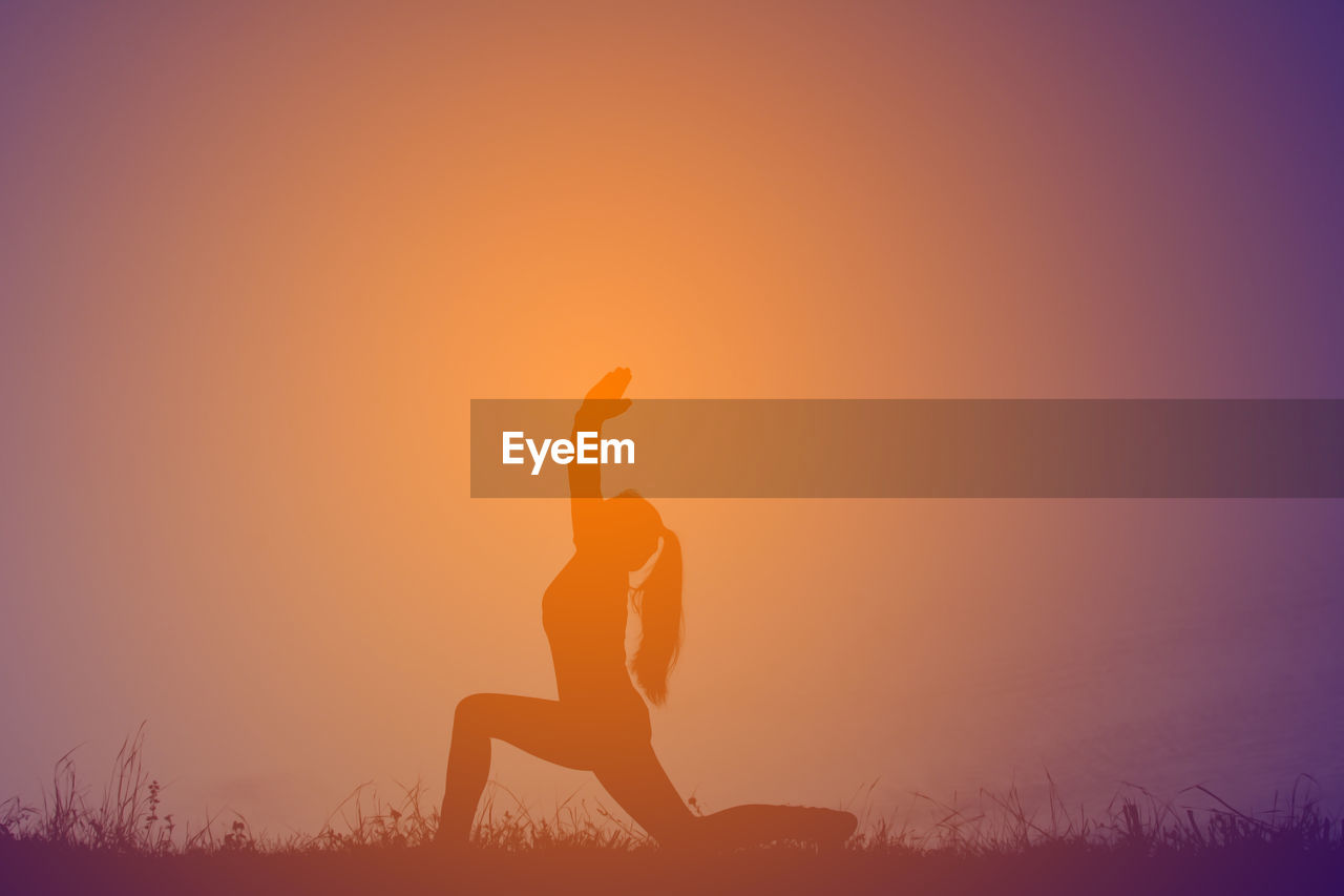 Silhouette woman doing anjaneyasana on field during sunset