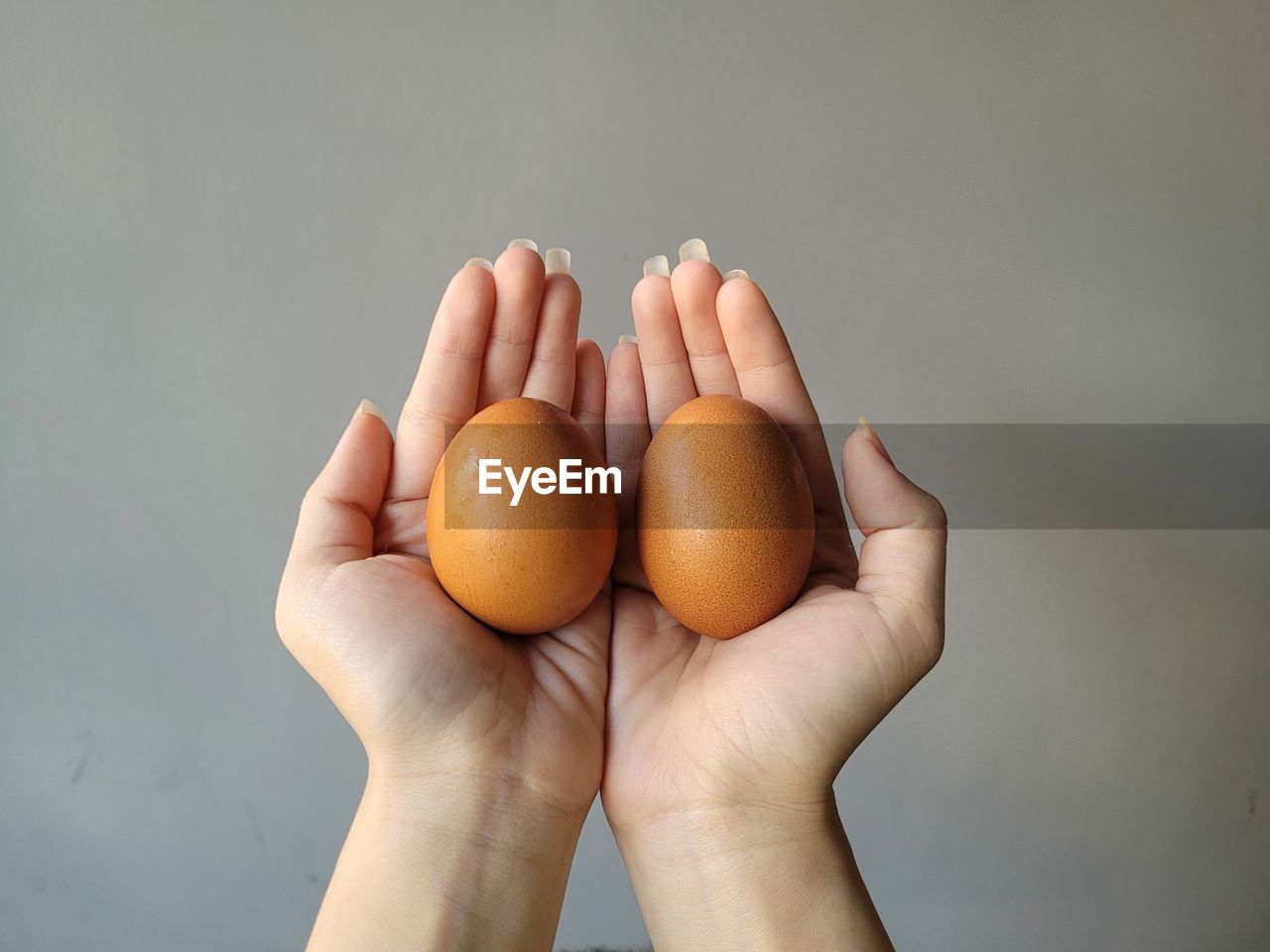 food, hand, food and drink, healthy eating, wellbeing, freshness, gray background, studio shot, holding, one person, close-up, egg, indoors, adult, raw food, gray, organic, limb, fragility, copy space, lifestyles, group of objects, personal perspective