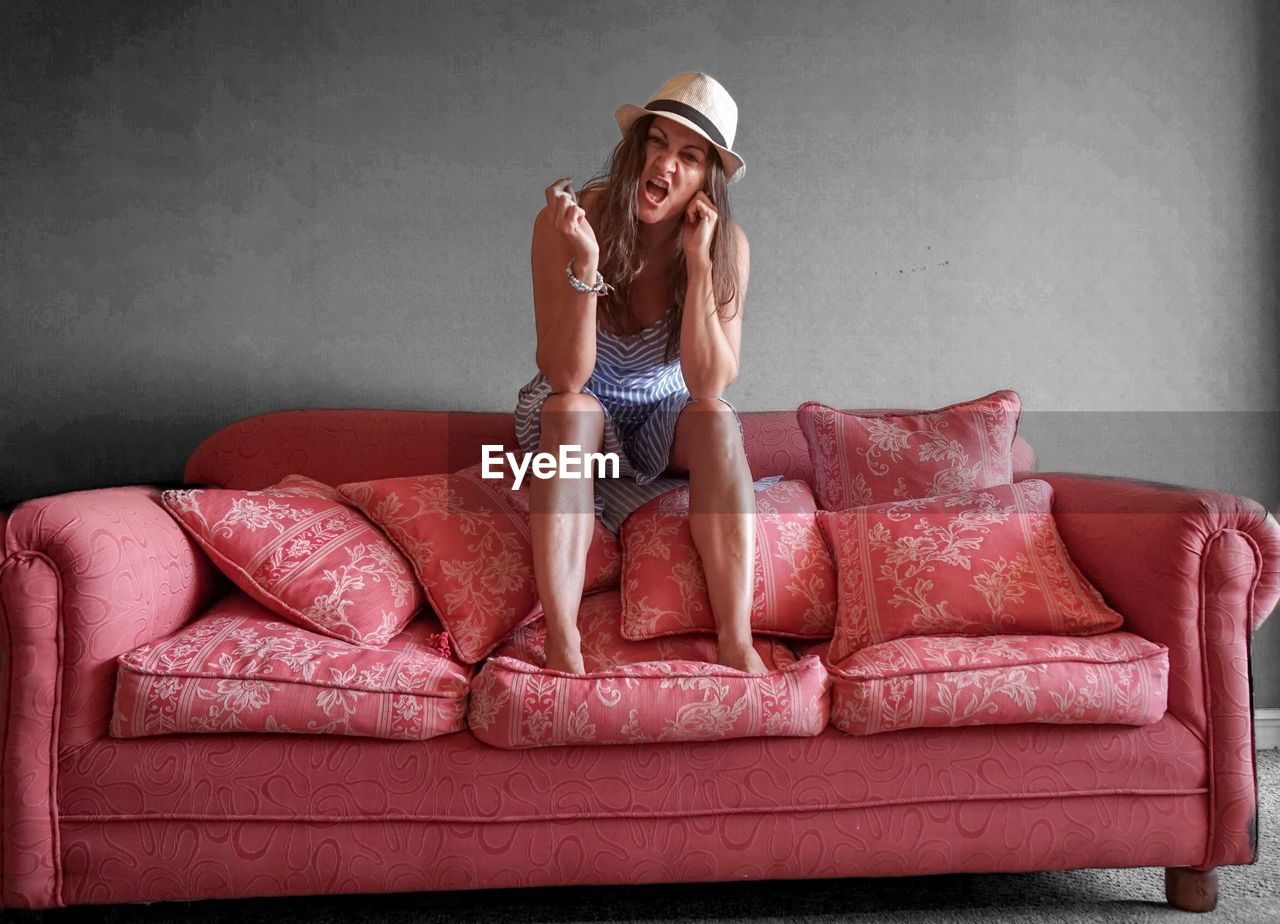 Young woman making face on sofa at home