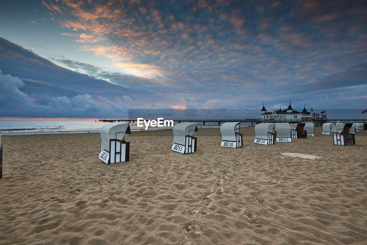 HOODED BEACH CHAIRS ON SAND AGAINST SKY