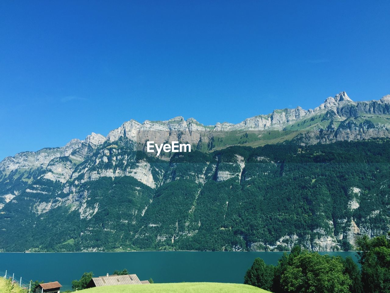 Scenic view of mountain and lake against clear blue sky