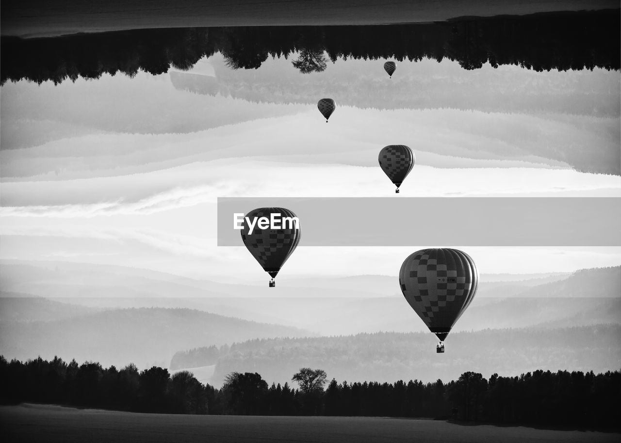 HOT AIR BALLOON FLYING OVER SILHOUETTE TREES