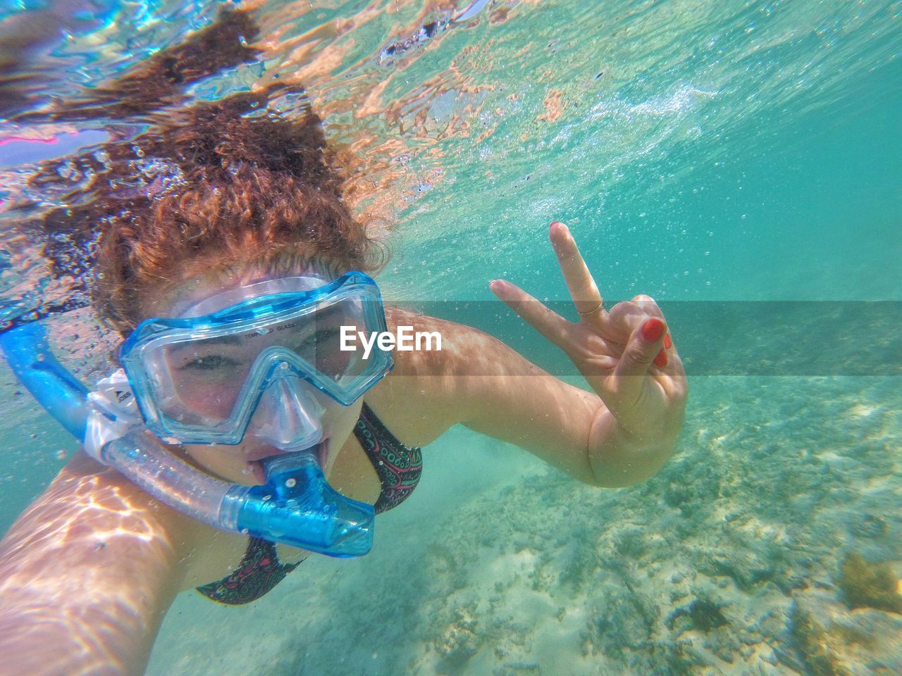 Portrait of woman gesturing peace sign while snorkeling in sea