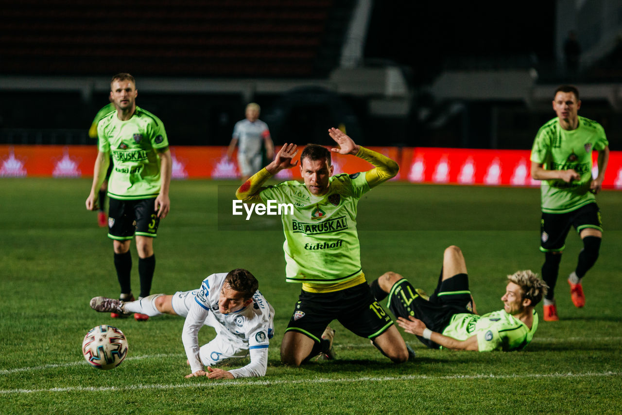 GROUP OF PEOPLE PLAYING SOCCER BALL ON GRASS