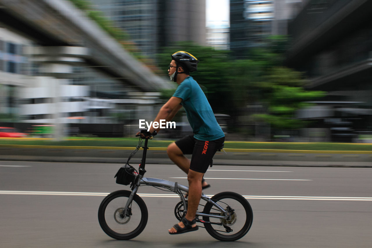 SIDE VIEW OF MAN RIDING BICYCLE ON ROAD